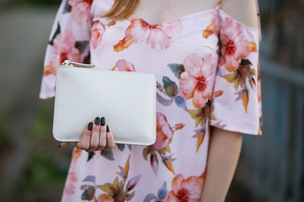 Foto closeup tiro de mão feminina segurando a bolsa de couro branco. espaço para texto