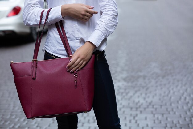 Closeup tiro de mulher segurando uma grande bolsa de couro vermelho. Espaço vazio