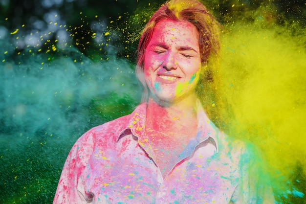 Closeup tiro de sorridente menina caucasiana brincando com tinta seca amarela e verde no Festival de Holi. Espaço vazio