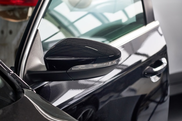Closeup tiro do espelho lateral do carro moderno preto na oficina de reparação automóvel