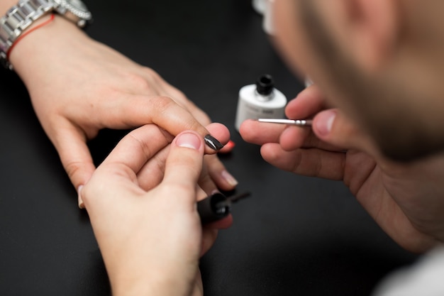 Closeup tiro homem fazendo manicure para mulher no salão de beleza