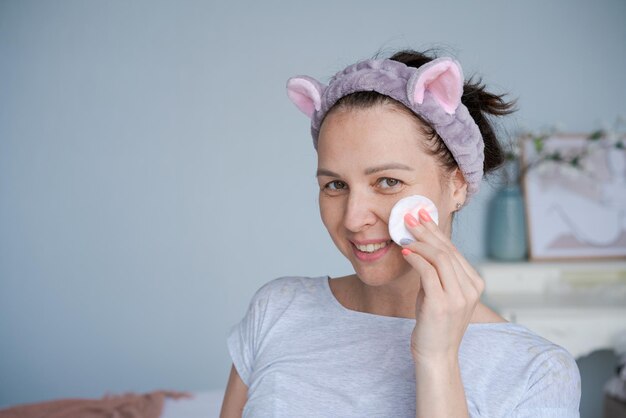 Closeup tiro na cabeça sorrindo linda mulher embrulhada em toalha aplicando toner