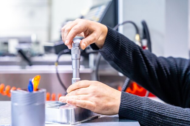 Foto closeup de un trabajador manual irreconocible que usa una herramienta para arreglar una pieza de metal en una fábrica moderna de cnc