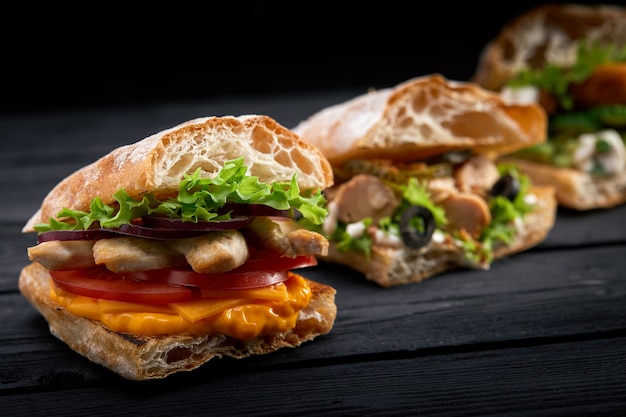 Closeup tres sándwiches o hamburguesas apetitosas diferentes sobre fondo de madera