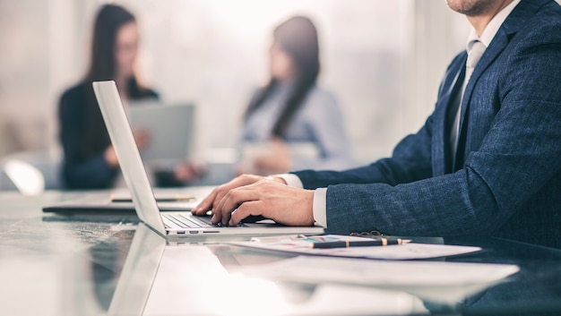 Closeup - um empresário de sucesso trabalhando em um laptop com dados financeiros no local de trabalho em um escritório moderno. A foto tem um espaço vazio para o seu texto