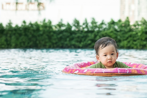 Closeup um menino sente-se em um barco para as crianças na piscina