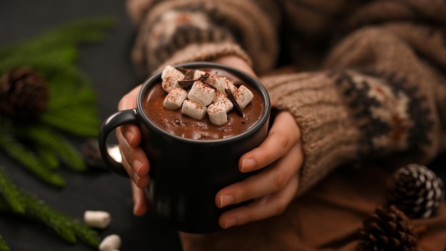 Closeup Uma mulher com as mãos segurando uma xícara de chocolate quente com marshmallow Bebidas especiais de inverno
