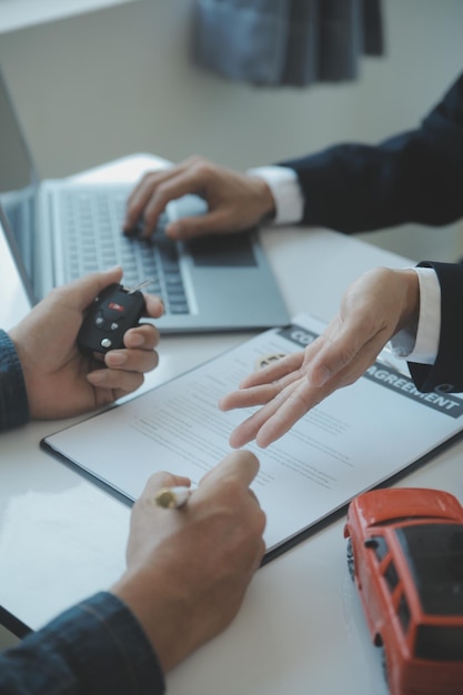 Closeup vendedor de carros asiáticos ou gerente de vendas se oferece para vender um carro e explica e lê os termos de assinatura de um contrato de carro e seguro