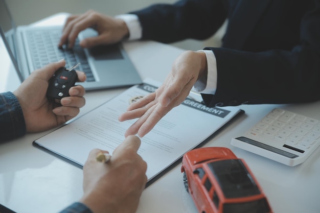 Closeup vendedor de carros asiáticos ou gerente de vendas se oferece para vender um carro e explica e lê os termos de assinatura de um contrato de carro e seguro