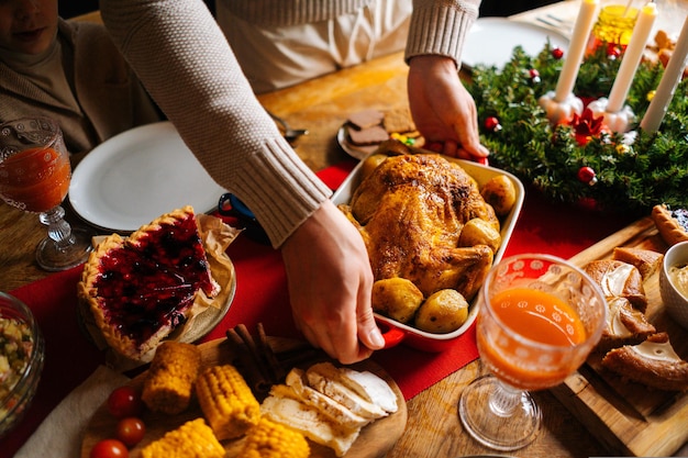 Closeup vista de alto ángulo de joven poniendo plato con pavo asado caliente en la mesa de la cena navideña