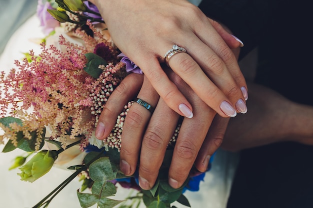 Closeup vista das mãos de recém-casados segurando um colorido buquê de casamento