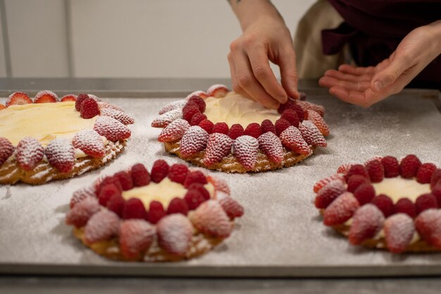 Foto closeup vista das mãos do chef de pastelaria decorando um bolo