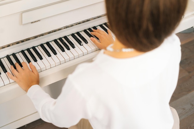 Closeup vista de trás do artista músico feminino irreconhecível tocando piano clássico em casa desfrutando de música virtuosa no tempo livre