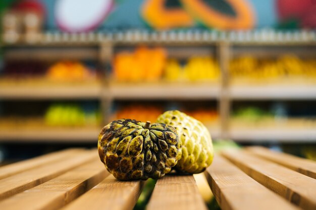 Closeup vista frontal da suculenta annona squamosa deitada em um palete de madeira com frutas e vegetais