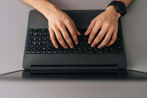 Closeup vista superior do empresário irreconhecível usando smartwatch digitando no computador portátil sentado na mesa no escritório