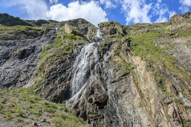 Closeup visualizar cenas de cachoeira nas montanhas, Parque Nacional Dombai, Cáucaso, Rússia, Europa. Paisagem de verão, clima ensolarado, céu azul dramático e dia ensolarado