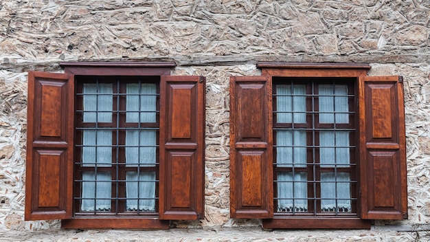 Closeup Wand eines Steinhauses mit Holzfenstern und Fensterläden Alte europäische Architektur