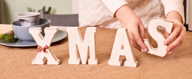 Closeup XMAS Holzbuchstaben auf festlich gedeckten Tisch. Frohe Weihnachten und Neujahrsfeier zu Hause