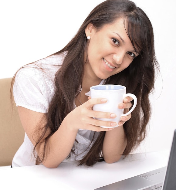 Closeup.young mujer con taza de té sentado en el lugar de trabajo.aislado en blanco