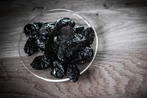 Closeupprunes em uma tigela e muesli em uma mesa de madeira