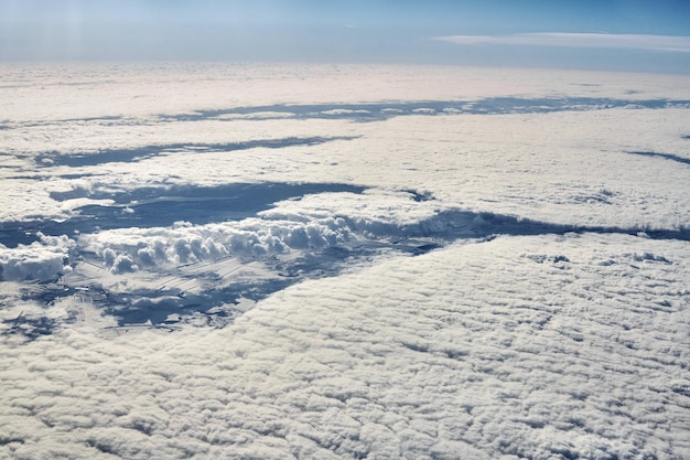 Cloudscape aus der Luft über Wolken bis zu schneebedeckten Flüssen, Straßen, Städten und Feldern, Winterluft