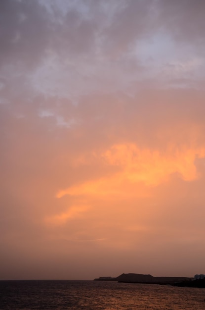 Cloudscape, nuvens coloridas ao pôr do sol perto do oceano