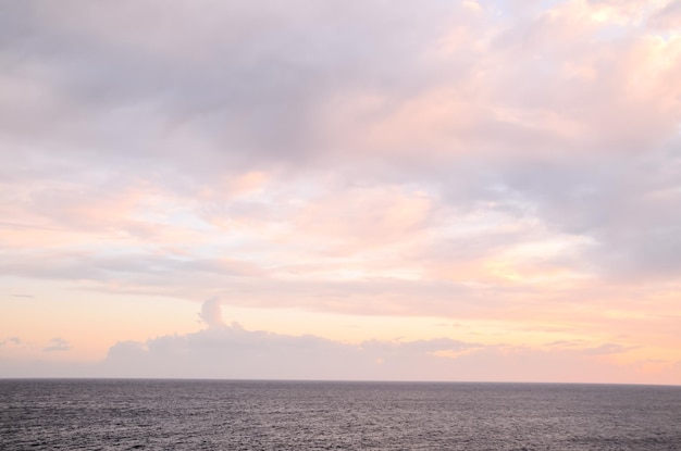 Cloudscape, nuvens coloridas ao pôr do sol perto do oceano