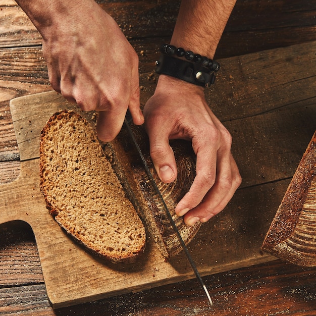 Clous up Man schneidet frisch gebackenes Brot