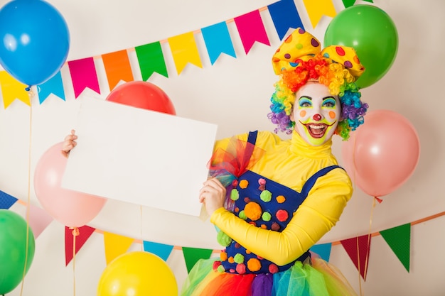 Clownmädchen an einem Feiertag, der einen weißen Teller für Inschriften hält