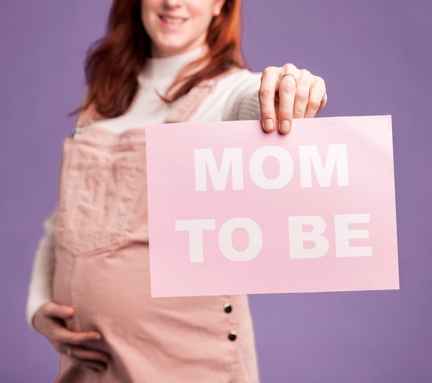 Foto clsoe-up mujer embarazada sosteniendo papel con mamá para ser mensaje