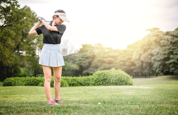 Club de golf de balanceo del jugador de golf asiático de la mujer en espacio abierto