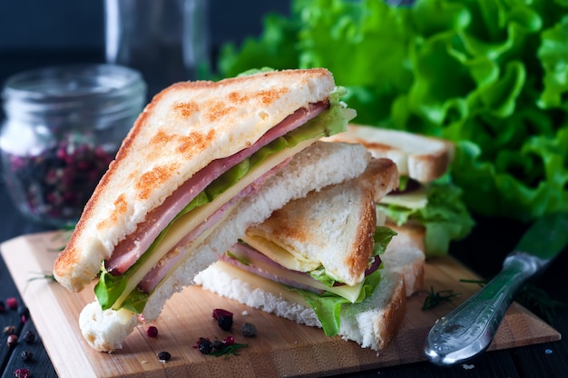 Club Sandwich mit einem Salat auf Holzplatte