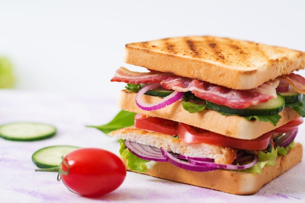 Club Sandwich mit Hühnerbrust, Speck, Tomate, Gurke und Kräutern