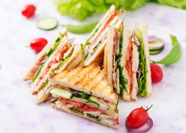 Club Sandwich mit Hühnerbrust, Speck, Tomate, Gurke und Kräutern