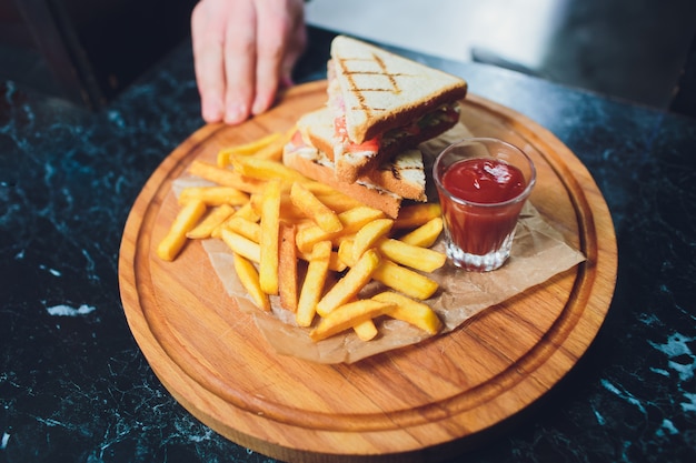 Club Sandwich mit Käse, Gurken, Tomaten und geräuchertem Fleisch. Mit Pommes Frites garniert.