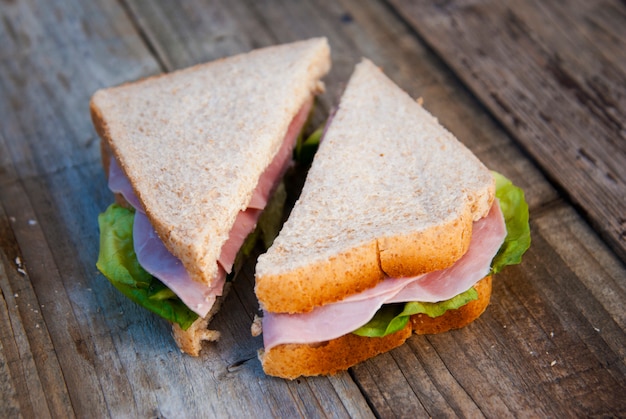 Club Sandwich mit Schinken und Gemüse. Rustikales Holz.