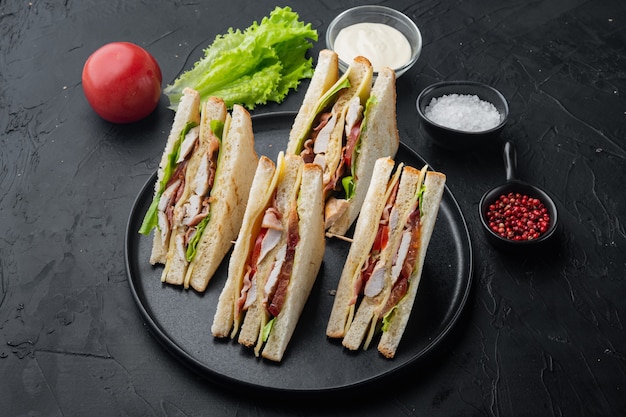 Club Sandwich Panini mit Schinken, frischer Tomate, Käse, auf schwarzem Hintergrund