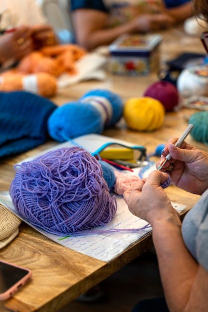 Clube de crochê Mãos de uma idosa tricotando com lã