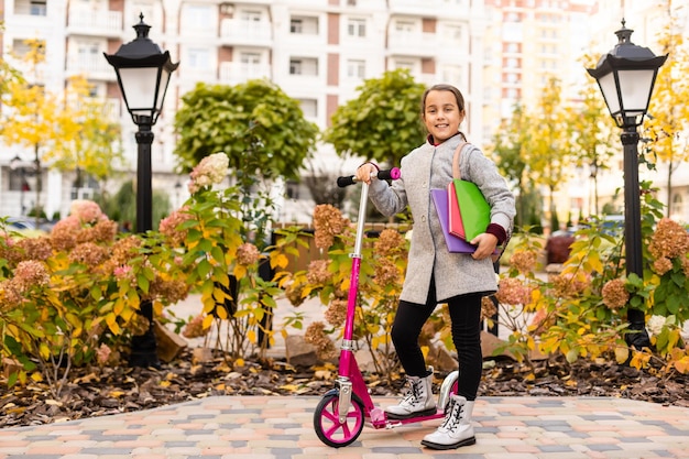 Clube escolar. Educação moderna. Escola privada. Adolescente com mochila. Aluna sorridente elegante. Menina na moda colegial carrega fundo de prédio escolar de mochila. Cotidiano da colegial.