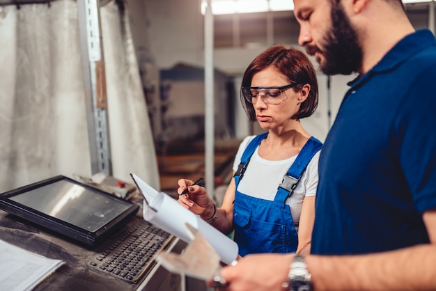 Cnc-Maschinenbediener und Wirtschaftsingenieur, die Produktzeichnung überprüfen