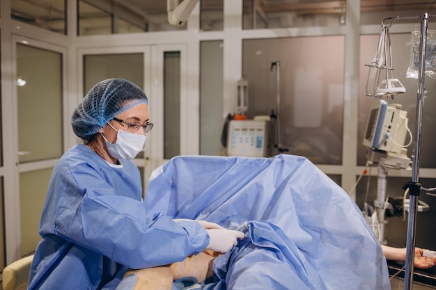 Foto coagulação a laser endovenosa para tratamento de varizes e máquina de ultrassom cirurgião vascular com fibra óptica de laser vermelho evlt para tratamento de tromboflebite das pernas em sala de cirurgia