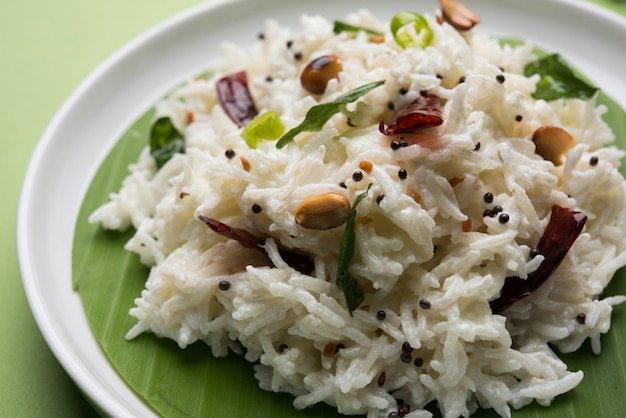 Coalhada de arroz ou Dahi Bhat OU Chawal com folha de curry, amendoim e pimenta-malagueta servida em uma tigela sobre um fundo temperamental. Foco seletivo