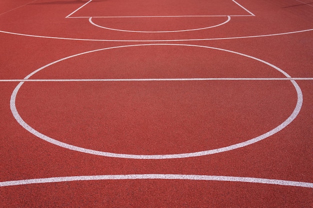 Cobertura de plástico vermelho nos círculos do playground e na quadra de basquete com listras brancas Preparando-se para a competição Local para uma inscrição