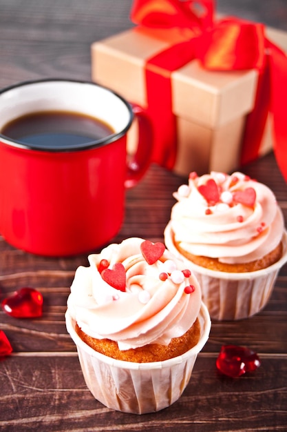 Cobertura de queijo creme de cupcakes de dia dos namorados decorada com doce de coração, caneca de café e caixa de presente. Conceito de dia dos namorados. Copie o espaço. Vista do topo.