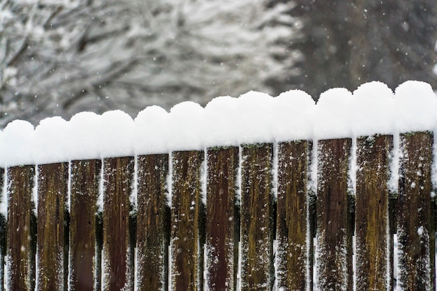 Coberturas de neve em cima de uma cerca de madeira.