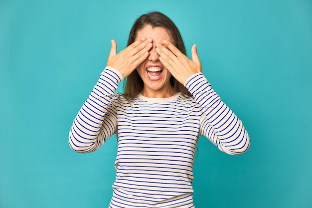 Cobre os olhos com as mãos sorri amplamente esperando uma surpresa