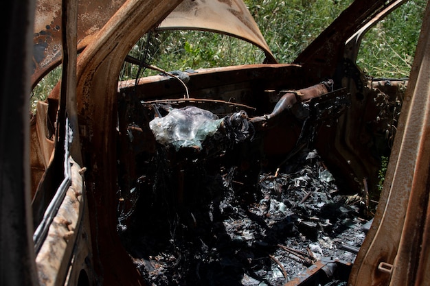 Coche abandonado y quemado en medio del bosque.