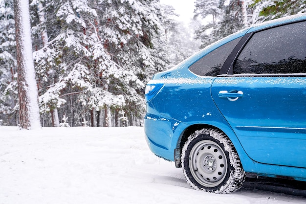 Coche azul en el bosque de nieve de invierno