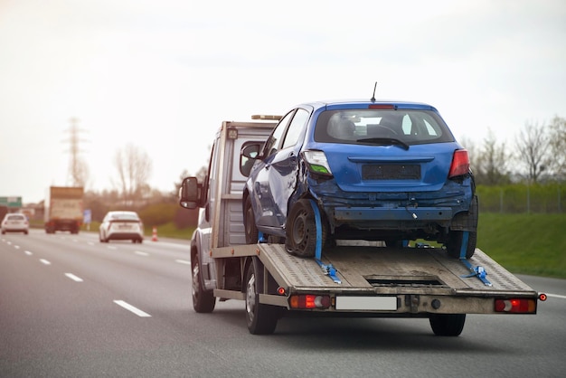 Un coche azul en un remolque está siendo remolcado por una grúa.