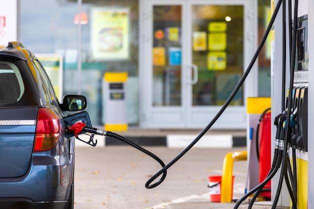 Coche azul repostando en la gasolinera en el primer plano del día de verano